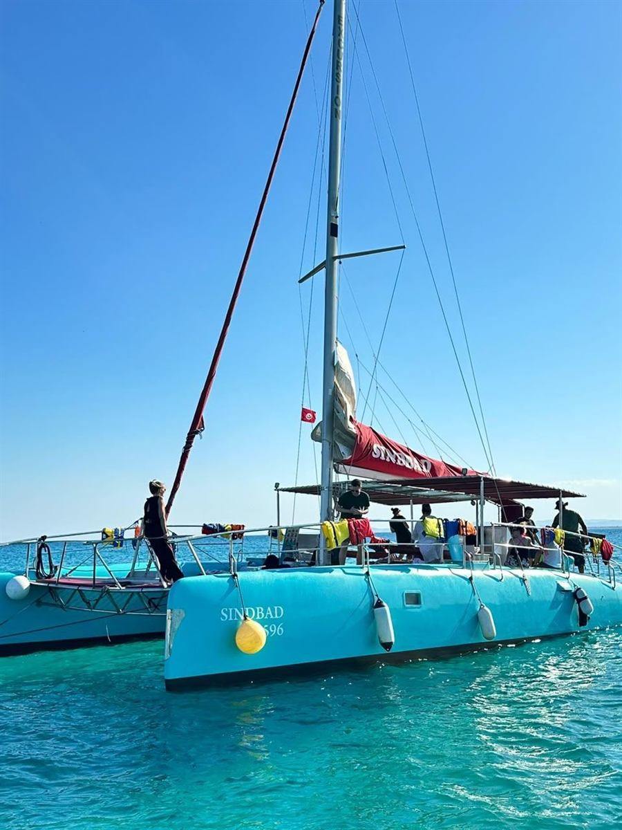 At anchor in turquoise water, life jackets hung along the rail