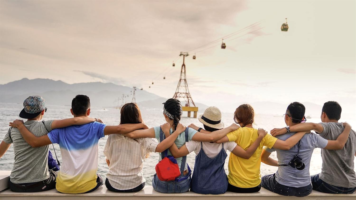 A group of friends raising their arms on a boat in the sunshine